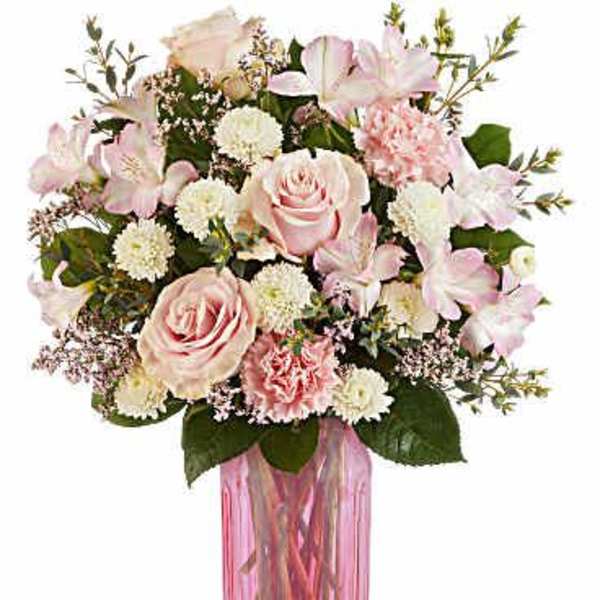 Pink roses and white flowers arranged in a pink glass vase