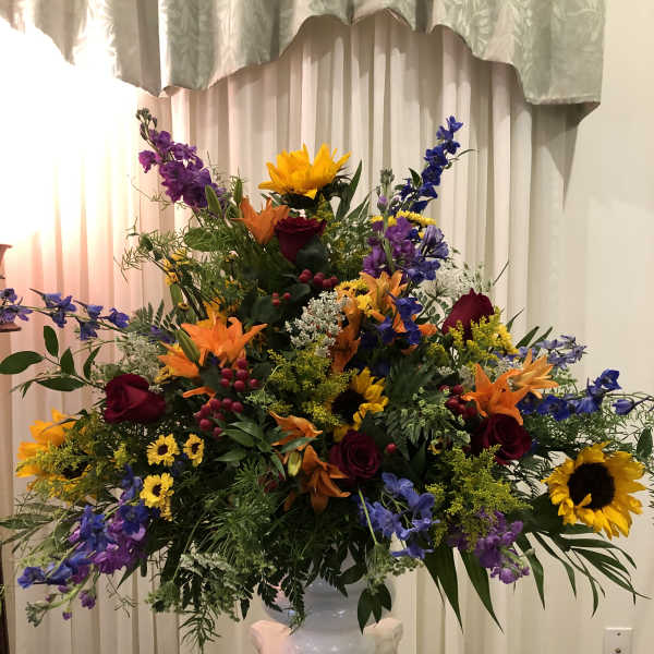 Large mixed flower arrangement in a white urn