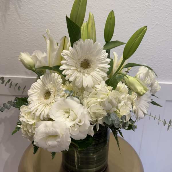 White floral arrangement with gerbera daisies and lilies in a dark vase