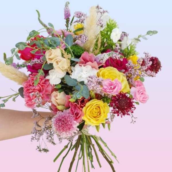 Handheld bouquet of pink, yellow, white, and red flowers