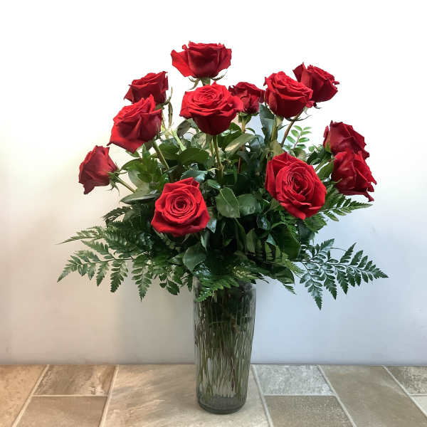 Red roses arranged in a tall glass vase
