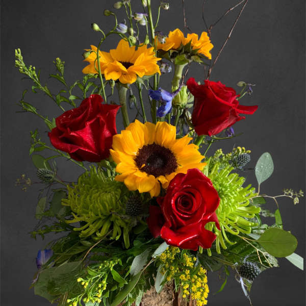 Tall bouquet with red roses and yellow sunflowers in a rustic wood base