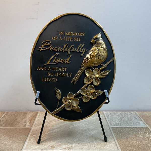 Oval memorial plaque with a bird and flowers on a stand