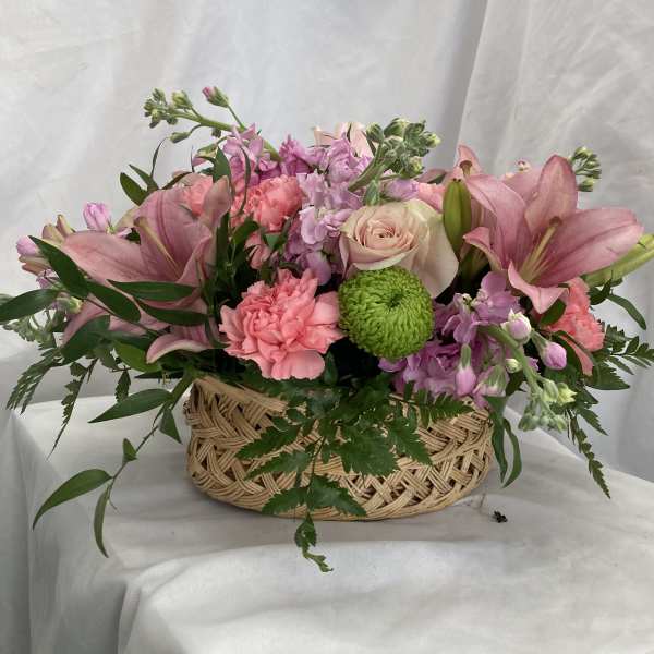 Pink lilies, roses, and carnations in a woven basket