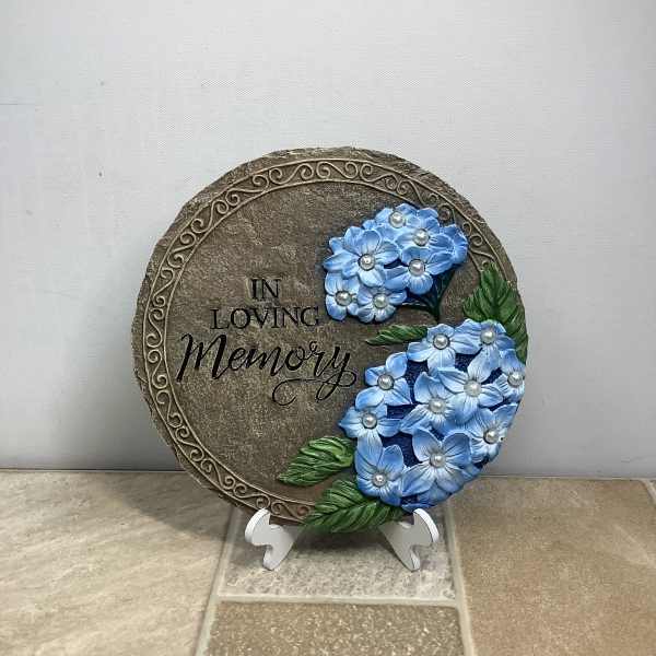 Round memorial plaque with blue flowers and the words "In Loving Memory"