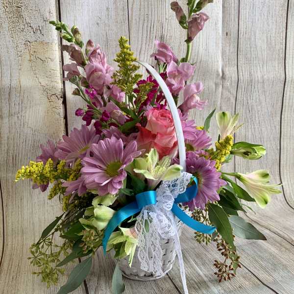 Basket arrangement of pink and purple flowers with a blue ribbon