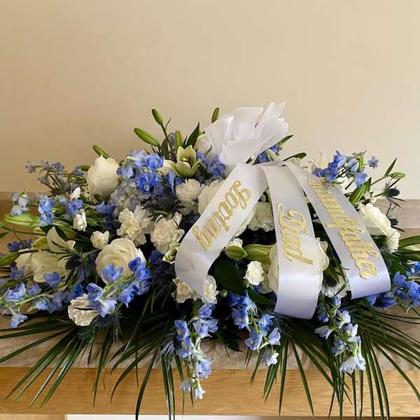 White and blue funeral spray with a memorial ribbon