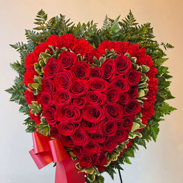 Heart-shaped red rose arrangement with a red ribbon