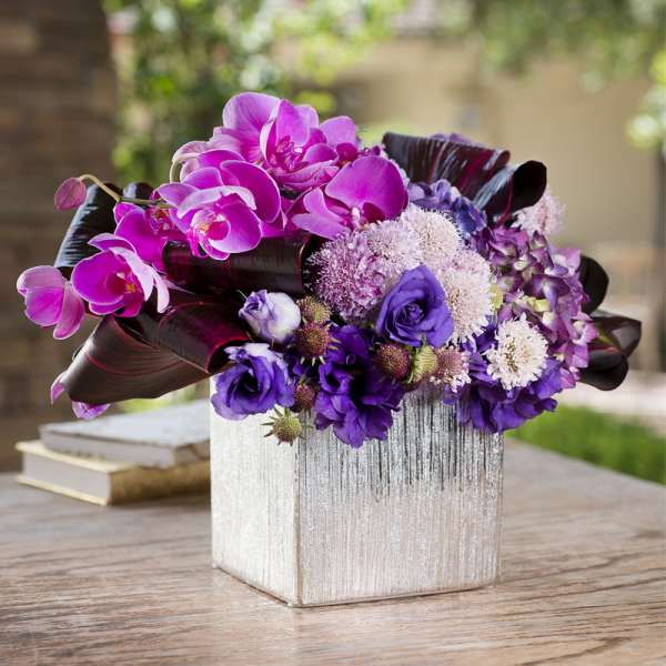 Purple orchid and mixed flower arrangement in a silver square vase