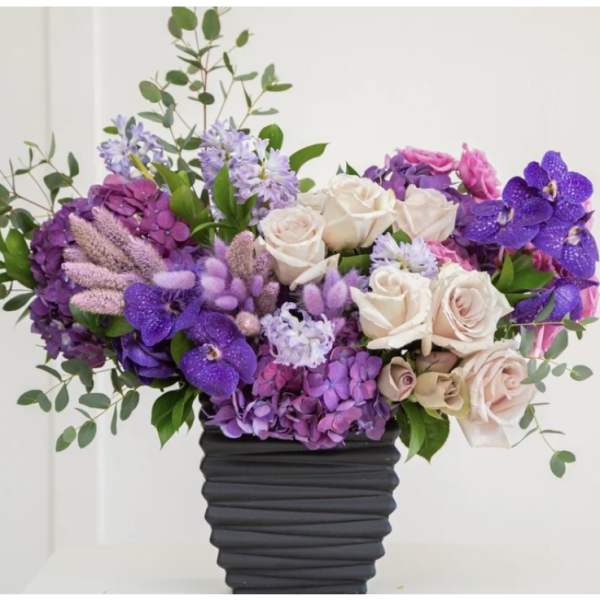 Purple and blush floral arrangement in a dark vase