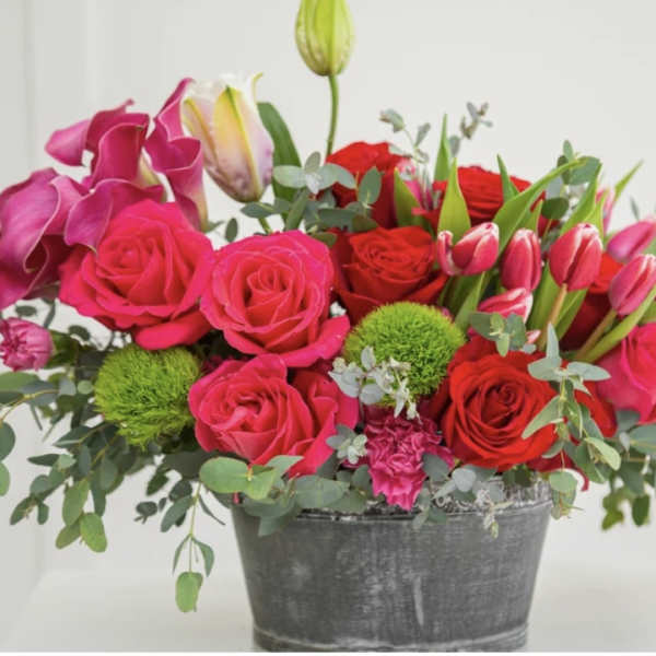Bright mixed bouquet of pink and red flowers in a metal bucket
