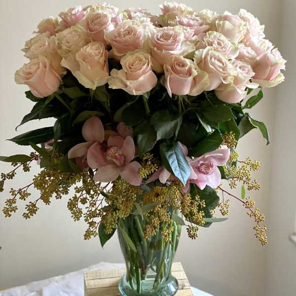 Bouquet of pale pink roses and orchids in a glass vase