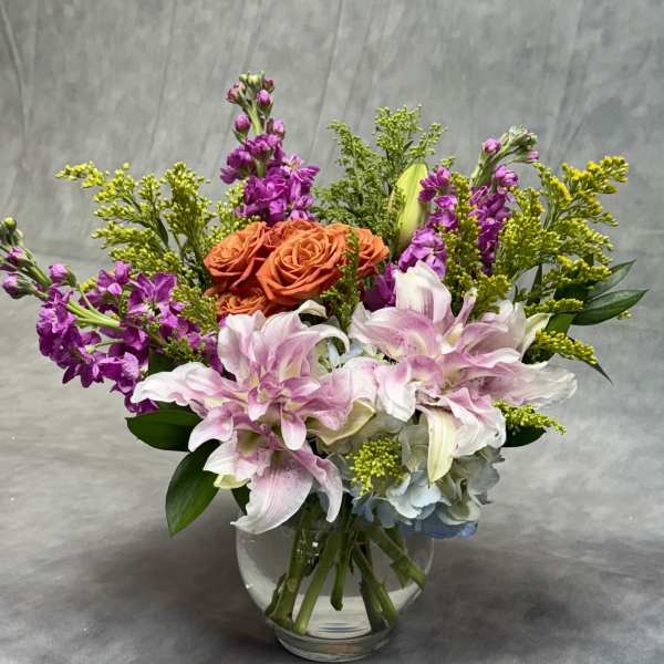 Bouquet of orange roses and pink lilies in a clear glass vase