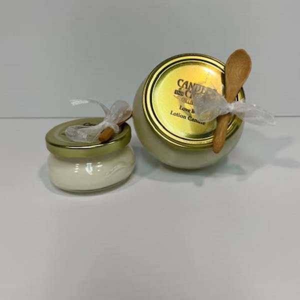 Two small candle jars with gold lids and wooden spoons tied on top