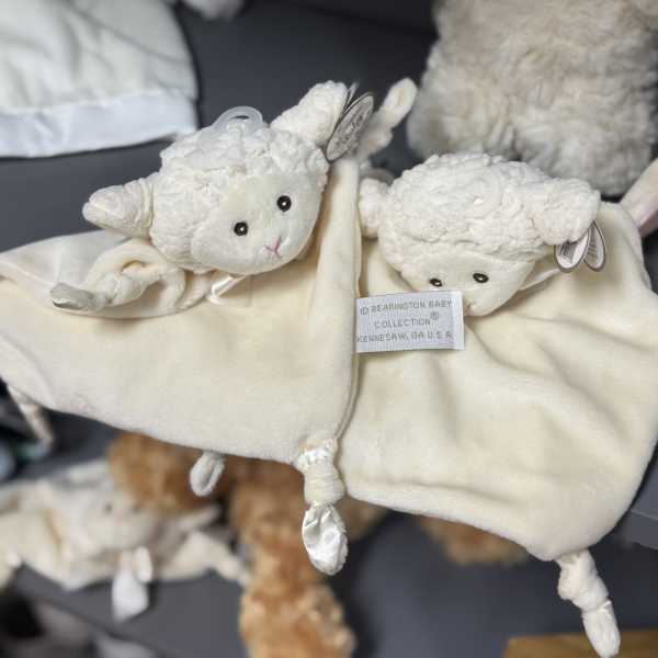 Two cream-colored plush lamb toys with a blanket