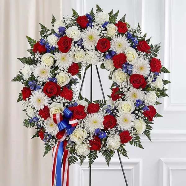 Circular standing wreath of red, white, and blue flowers on an easel