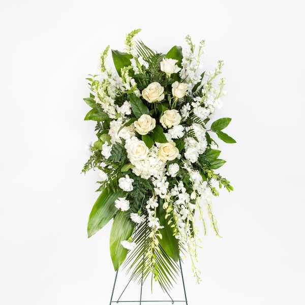 Standing spray of white roses and mixed white flowers on an easel