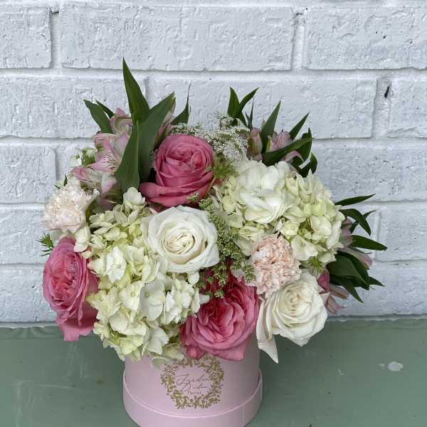 Pink and white roses with hydrangeas in a pink round box