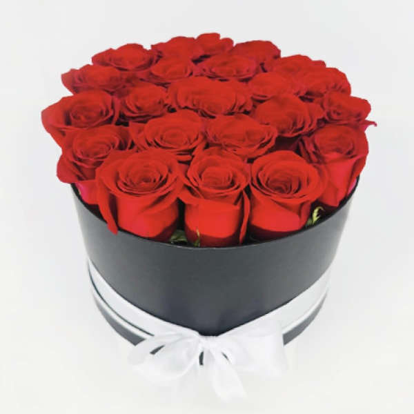 Red roses arranged in a black round box with a white ribbon