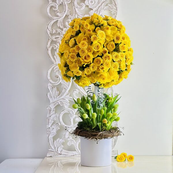 Tall yellow rose arrangement with green buds in a white vase
