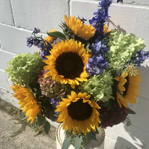 Bouquet of sunflowers and blue-purple flowers in a white container