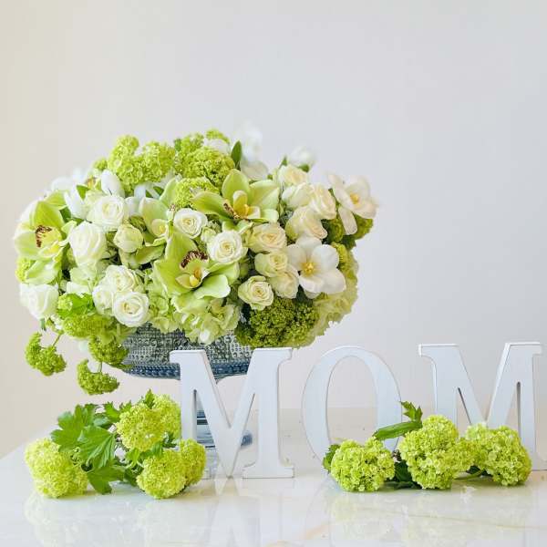 Green and white floral arrangement in a silver vase with MOM letters