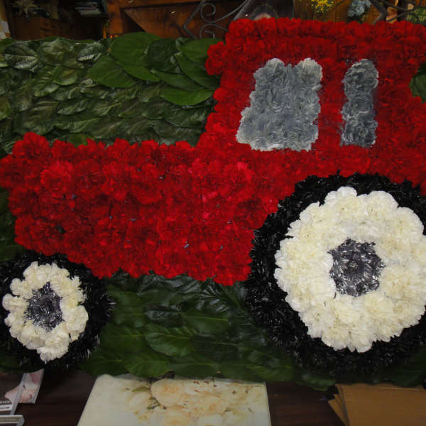 Floral arrangement shaped like a red truck with white wheels