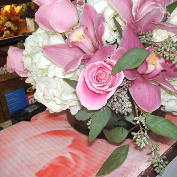 Pink orchids and roses arranged with white hydrangeas in a low vase