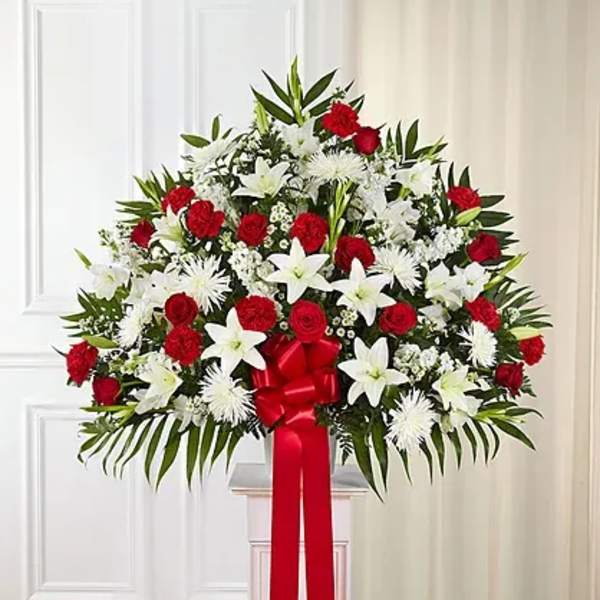 Standing floral spray of red and white flowers with a red ribbon