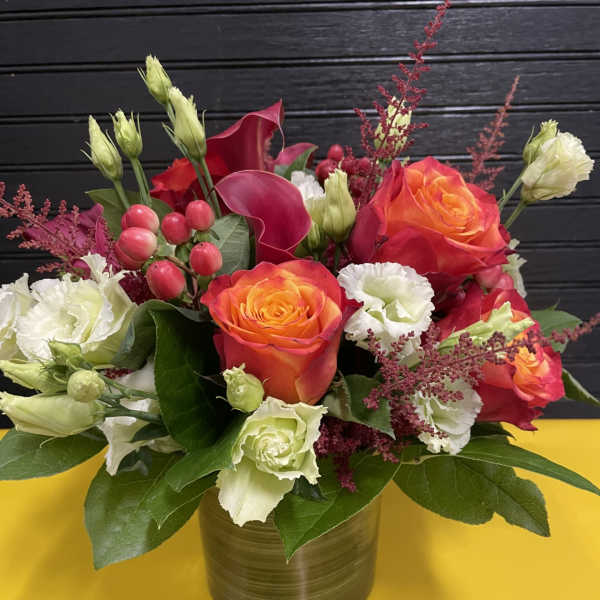Bouquet of orange roses and white lisianthus in a gold vase