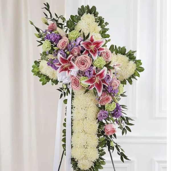 Standing floral cross with pink roses, lilies, and white blooms