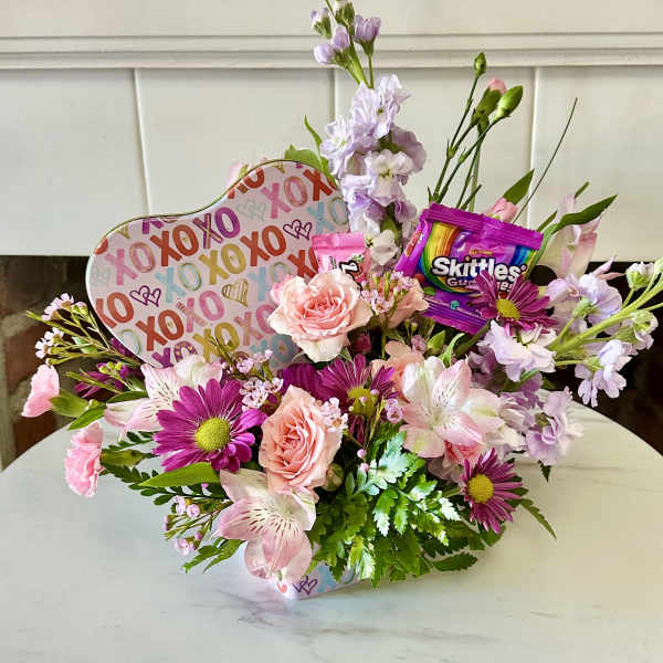 Mixed pink and lavender flower arrangement with candy and a heart-shaped XOXO sign