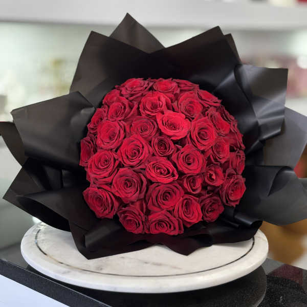 Round bouquet of red roses wrapped in black paper