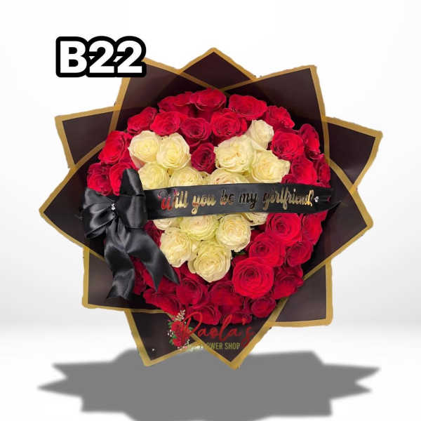 Heart-shaped bouquet of red and cream roses with a black ribbon