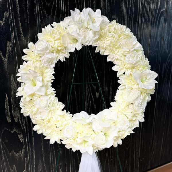 White floral wreath on a stand with a tulle ribbon