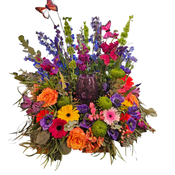 Colorful mixed flower arrangement with butterflies and a purple glass vase