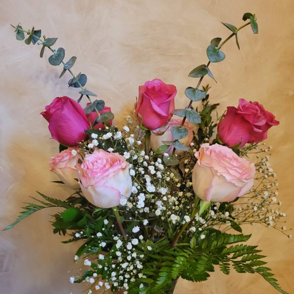 Pink roses in a glass vase with baby's breath and eucalyptus