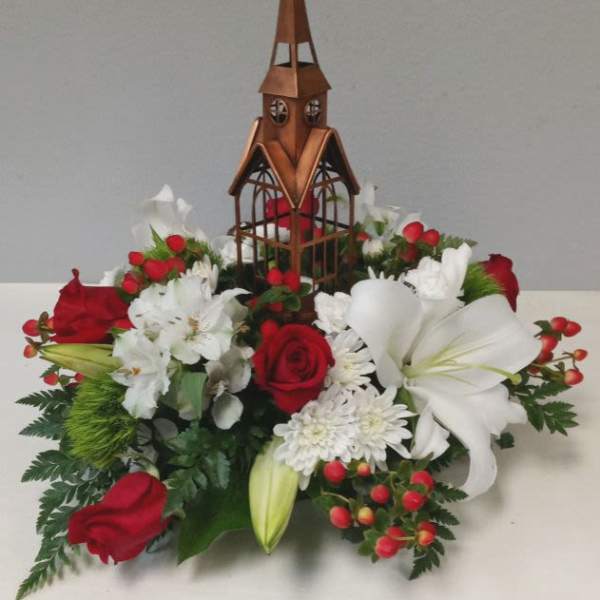 Red and white floral arrangement with a wooden church centerpiece