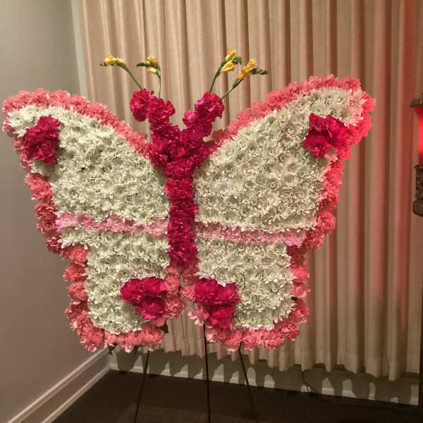 Butterfly-shaped floral display in pink and white on a stand