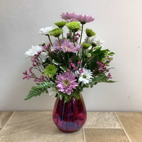 Pink and white daisy bouquet in a red glass vase