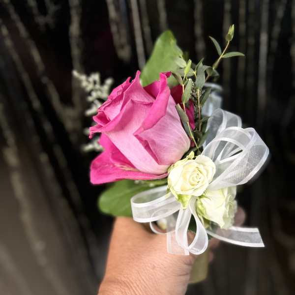 Pink rose boutonniere with white ribbon and small white roses