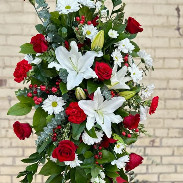 Standing floral spray with red roses, white lilies, and daisies