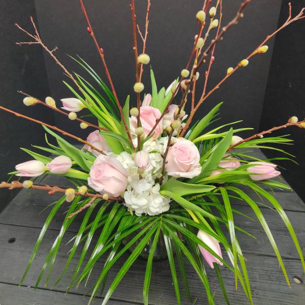 Pink roses and white hydrangea in a low arrangement with tall branches