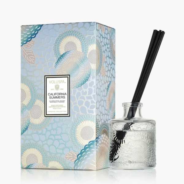 Reed diffuser in a glass bottle beside a patterned box
