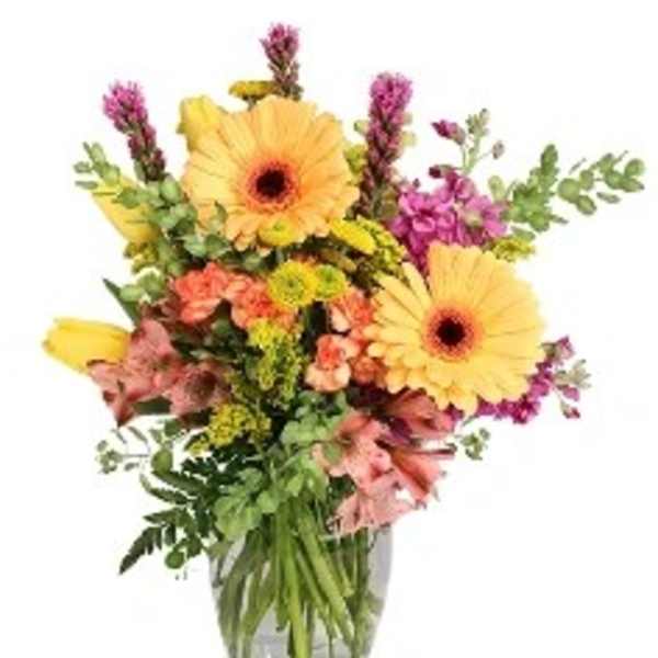 Bouquet of yellow gerbera daisies and pink mixed flowers in a glass vase