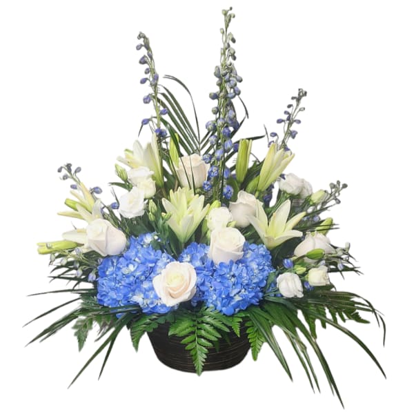 White roses and lilies with blue hydrangeas in a black basket
