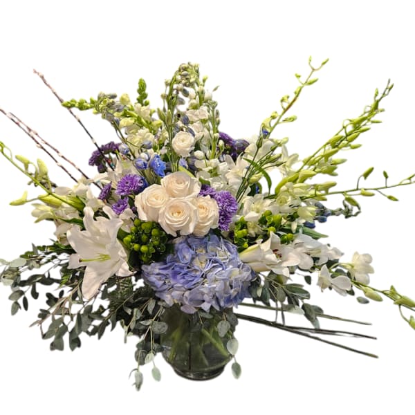 Mixed bouquet of white, blue, and purple flowers in a glass vase