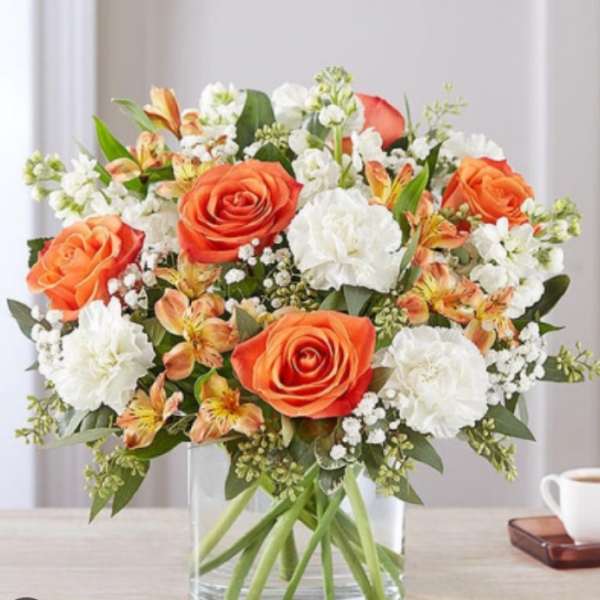 Orange and white rose bouquet in a clear glass vase