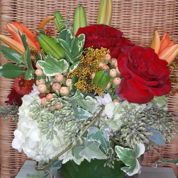 Red roses and lilies arranged in a square glass vase
