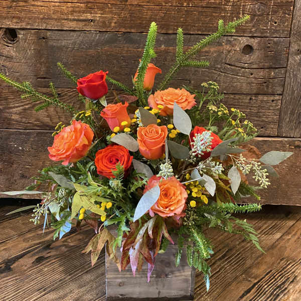 Orange and red rose arrangement in a rustic wooden box